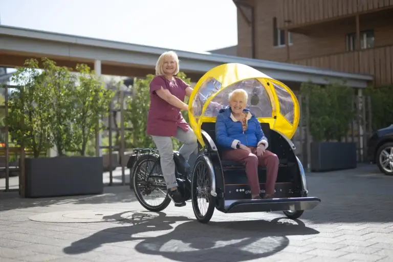 seniorin-gefahren-von-pflegefachfrau-fahrrad-heimet