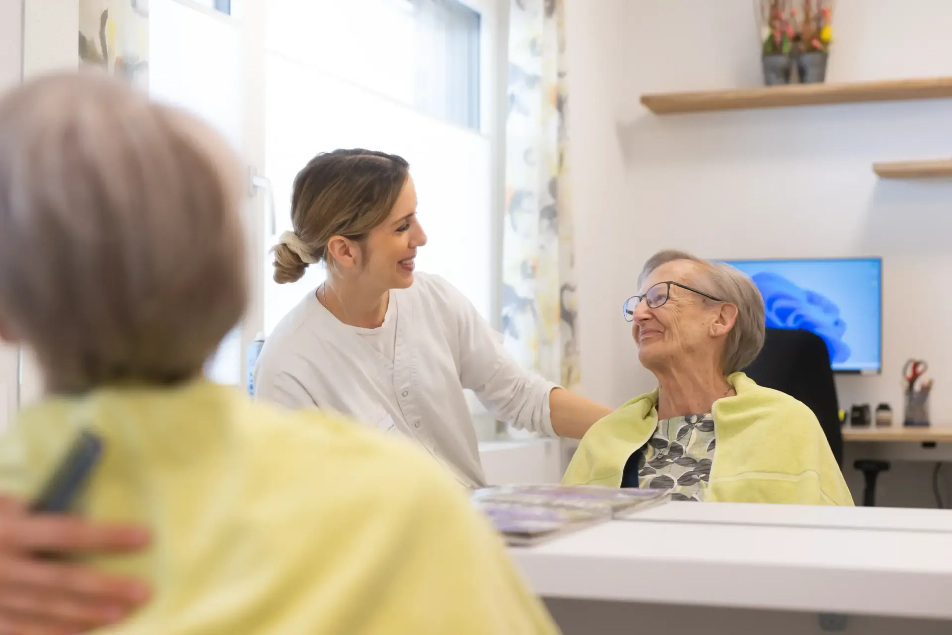 mitarbeiterin-und-aeltere-frau-schauen-sich-in-die-augen-spiegelbild-heimet
